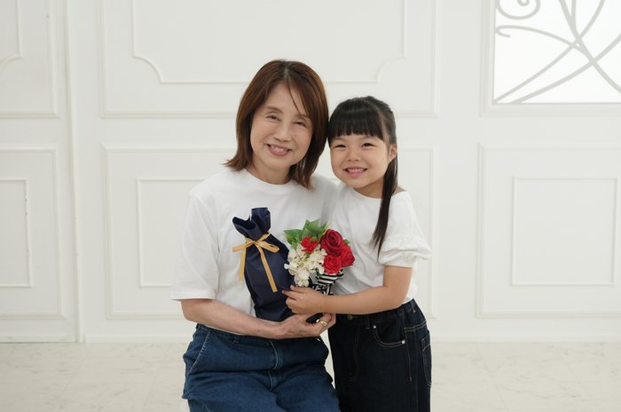 お花のギフトを持ったおばあちゃんとお孫さんの記念写真